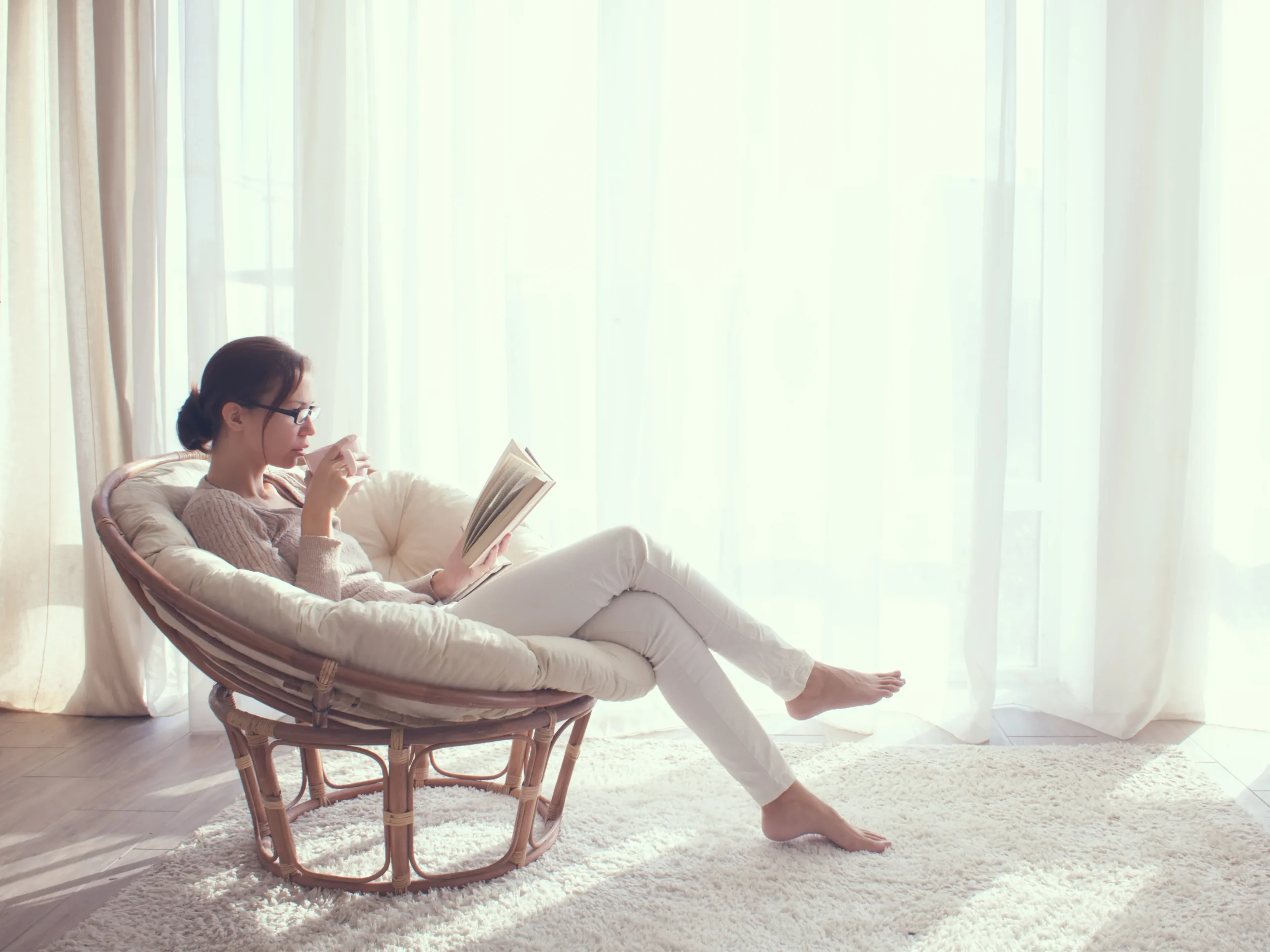 woman relaxing and drinking coffee by light window