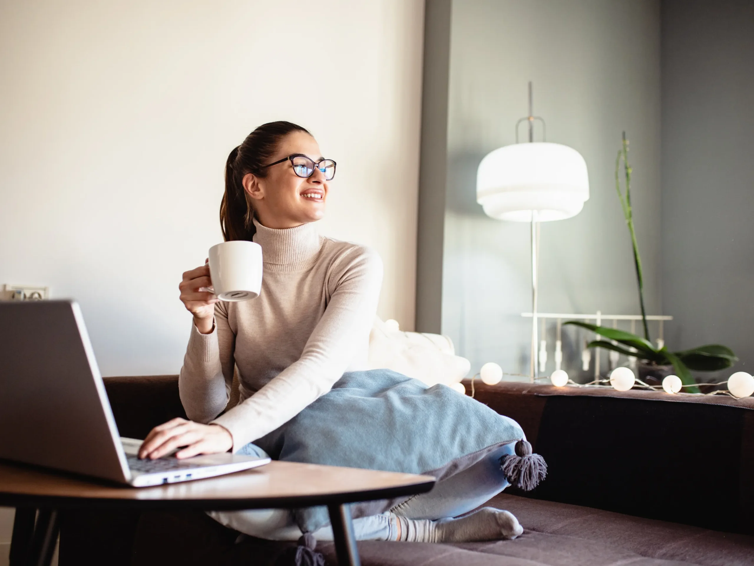 person enjoying comfort of home using laptop and drinking coffee