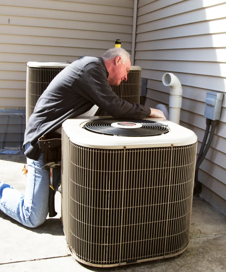 Man repairing AC unit outside of his home
