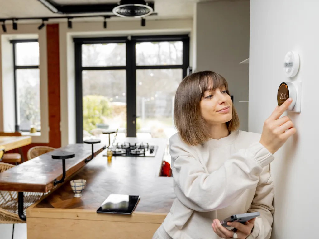 woman changing thermostat with smart home air conditioning system